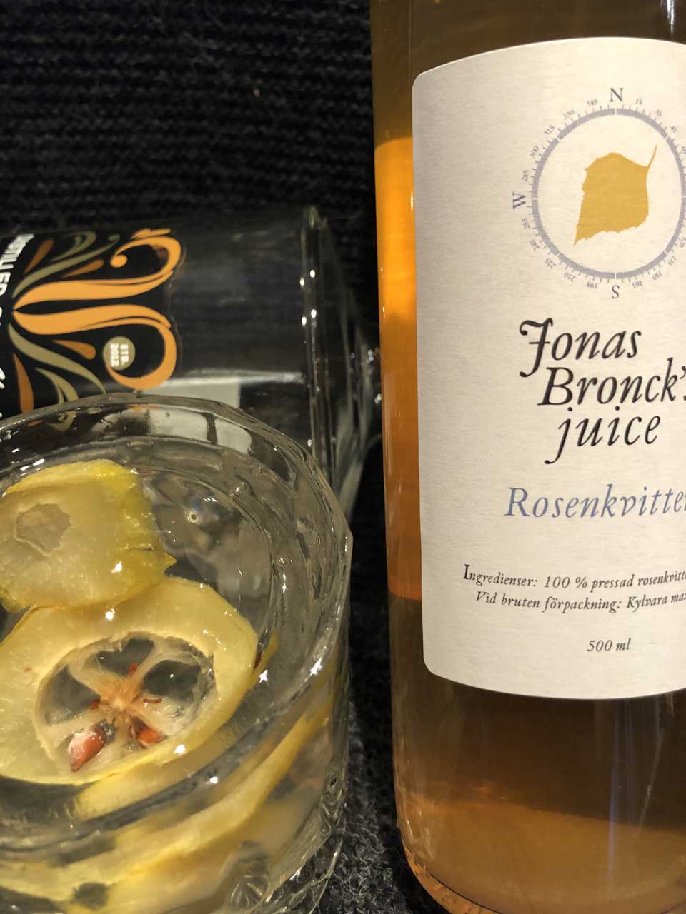 Flaska Jonas Broncks Rosenkvitten bredvid ett glas med citron skivor